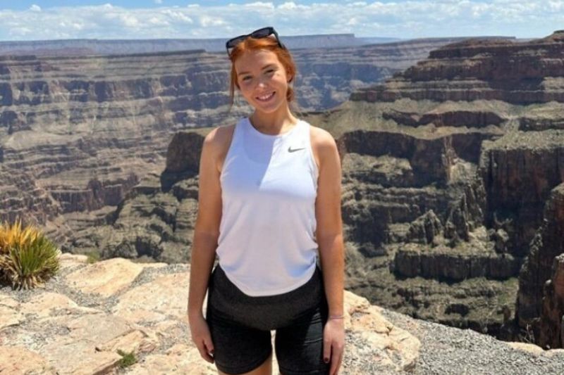 student standing outdoors in sunshine with a sandy landscape